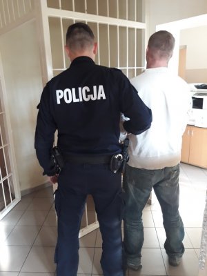 policjant prowadzi zatrzymanego