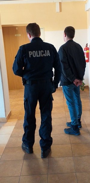 policjant podczas doprowadzania zatrzymanego