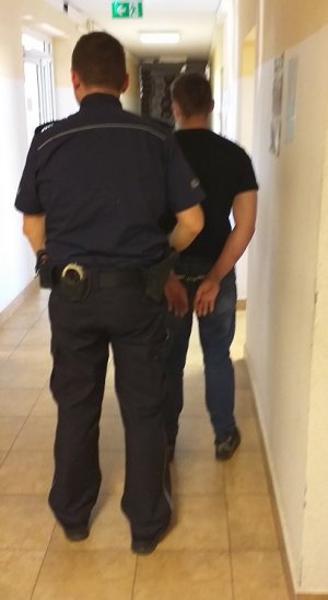 policjant podczas doprowadzania zatrzymanego