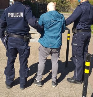 policjanci podczas doprowadzenia zatrzymanego