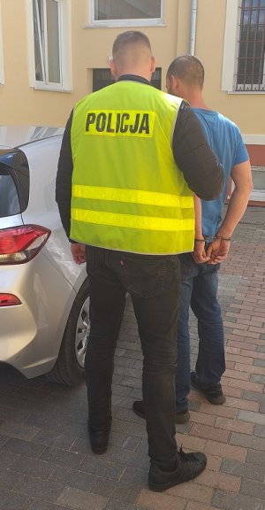 policjant podczas doprowadzania zatrzymanego