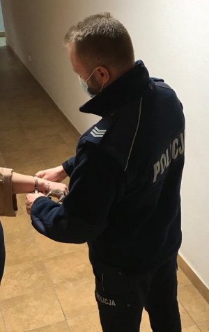 policjant podczas zakładania kajdanek służbowych