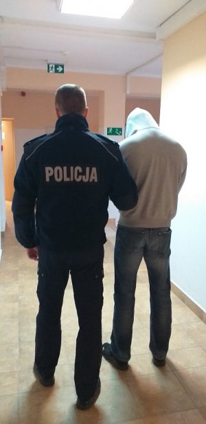 policjant podczas doprowadzania zatrzymanego