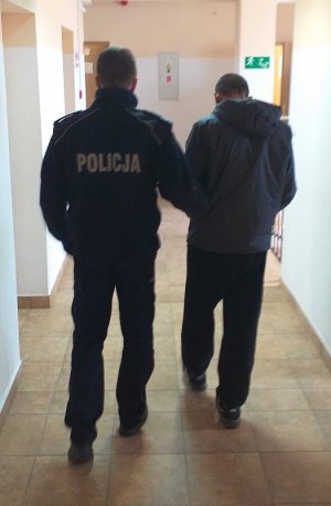 policjant podczas doprowadzania zatrzymanego