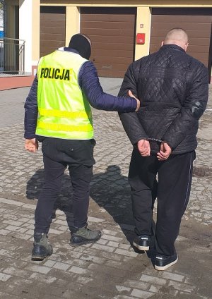 policjant podczas doprowadzania zatrzymanego