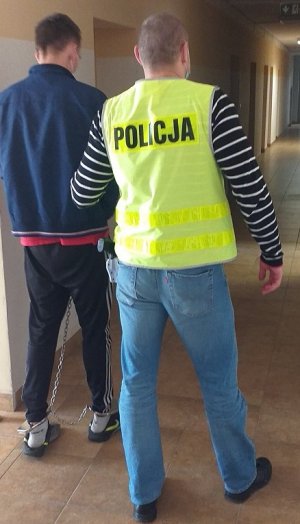 policjant podczas doprowadzania zatrzymanego