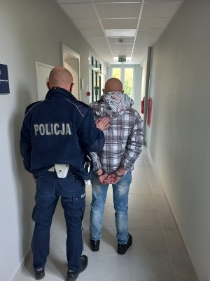 policjant podczas doprowadzania zatrzymanego