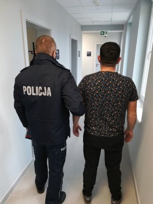 policjant podczas doprowadzania zatrzymanego