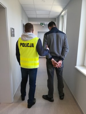 policjant podczas doprowadzania zatrzymanego