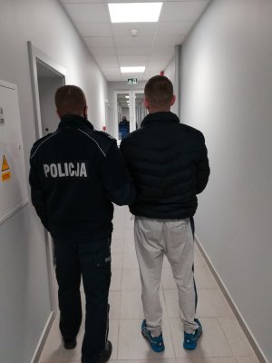 policjant podczas doprowadzania zatrzymanego