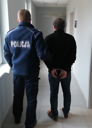 policjant podczas doprowadzania zatrzymanego