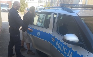 policjant podczas doprowadzania zatrzymanego