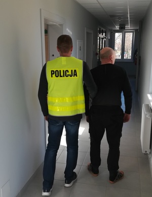 policjant podczas doprowadzania zatrzymanego