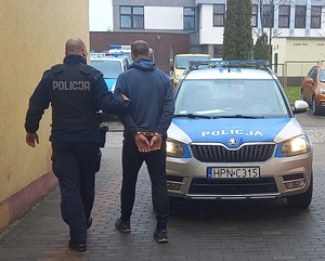 policjant podczas doprowadzania zatrzymanego