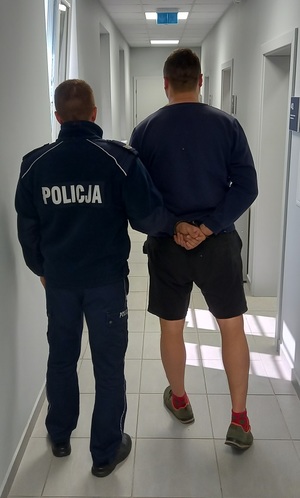 policjant podczas doprowadzania zatrzymanego