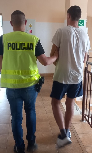 policjant podczas doprowadzania zatrzymanegi