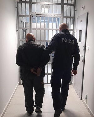 policjant podczas doprowadzania zatrzymanego