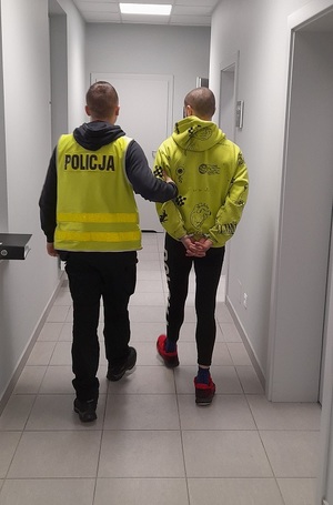 policjant podczas doprowadzania zatrzymanego