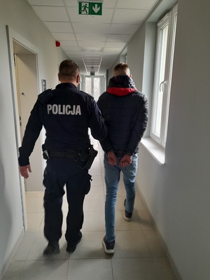 policjant podczas doprowadzania zatrzymanego