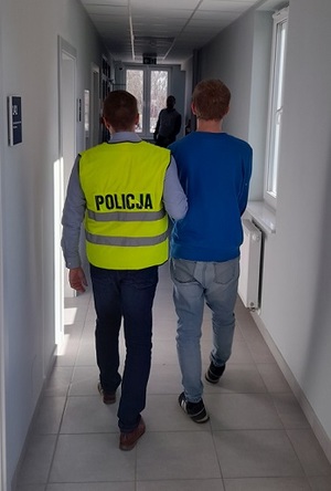 policjant podczas doprowadzania zatrzymanego