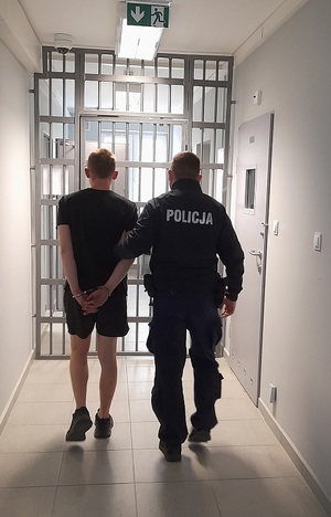 policjant podczas doprowadzania zatrzymanego