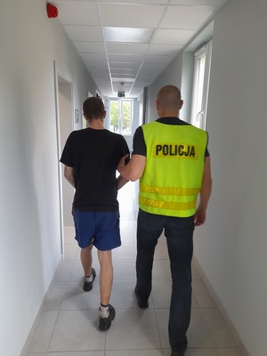 policjant podczas doprowadzania zatrzymanego