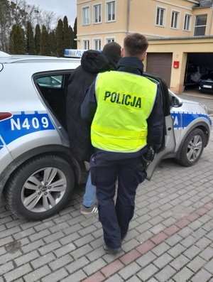 policjant podczas doprowadzania zatrzymanego