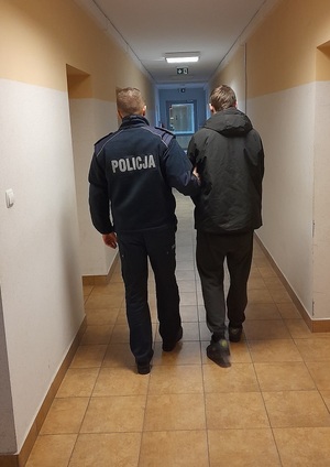 policjant podczas doprowadzania zatrzymanego