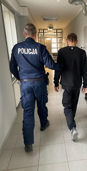 policjant podczas doprowadzania zatrzymanego