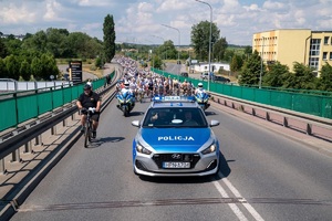 radiowóz i motocykle policyjne podczas zabezpieczenia przejazdu