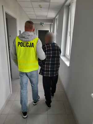 policjant podczas doprowadzania zatrzymanego