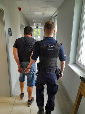 policjant podczas doprowadzenia zatrzymanego