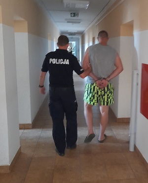 policjant podczas doprowadzania zatrzymanego