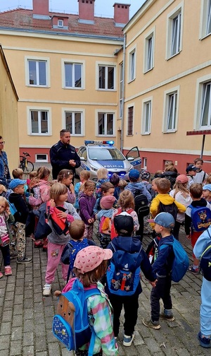 policjant i radiowóz policyjny podczas spotkania z dziećmi