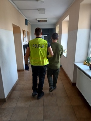 policjant podczas doprowadzenia zatrzymanego