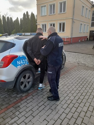 policjant podczas doprowadzania zatrzymanego