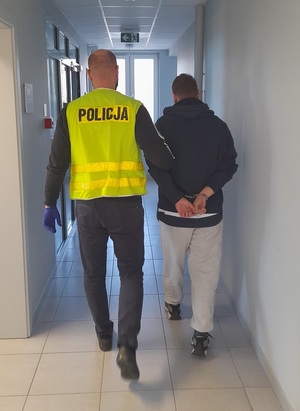 policjant podczas doprowadzania zatrzymanego