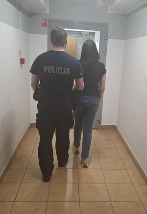 policjant podczas doprowadzania zatrzymanego