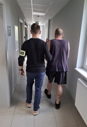 policjant podczas doprowadzania zatrzymanego