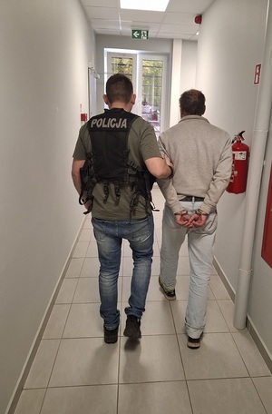 policjant podczas doprowadzenia zatrzymanego