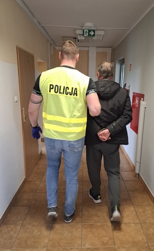 policjant podczas doprowadzenia zatrzymanego