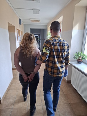 policjant podczas doprowadzania zatrzymanego