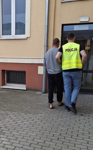 policjant podczas doprowadzenia zatrzymanego