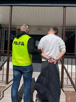 policjant podczas doprowadzania zatrzymanego