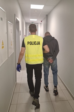 policjant podczas doprowadzania zatrzymanego