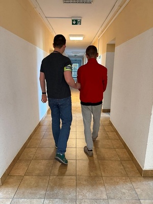 policjant podczas doprowadzenia zatrzymanego