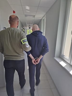 policjant podczas doprowadzenia zatrzymanego
