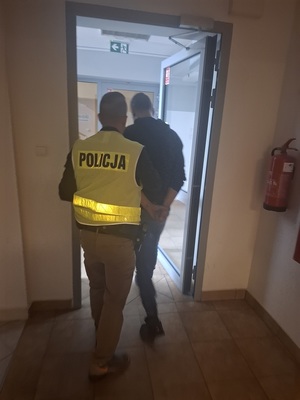 policjant podczas doprowadzania zatrzymanego