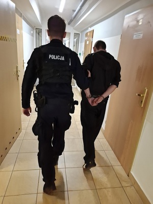 policjant podczas doprowadzania zatrzymanego