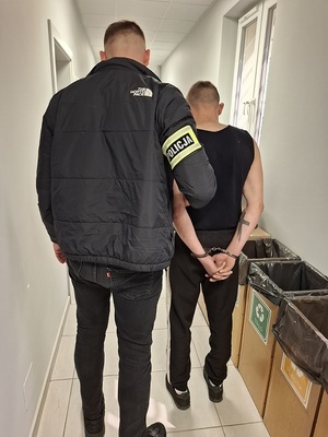 policjant podczas doprowadzania zatrzymanego